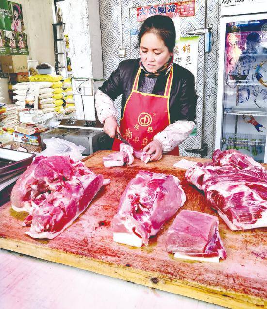 1月14日,市区城北农贸市场里的肉铺店主正忙着为顾客切肉.