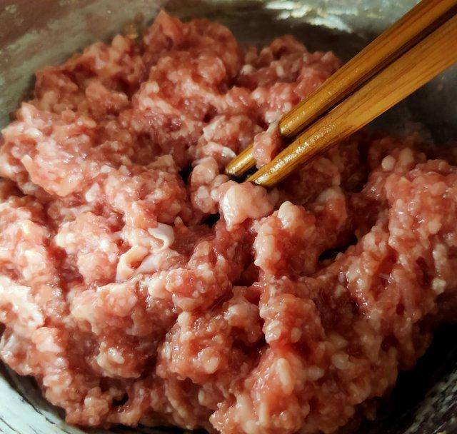 第8步,羊肉馅儿中分次少量倒入花椒水朝一个方向搅拌均匀.