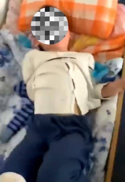 在被双手被反绑吊在柜子上的男孩不远处,就是一张儿童睡觉的床铺,其中