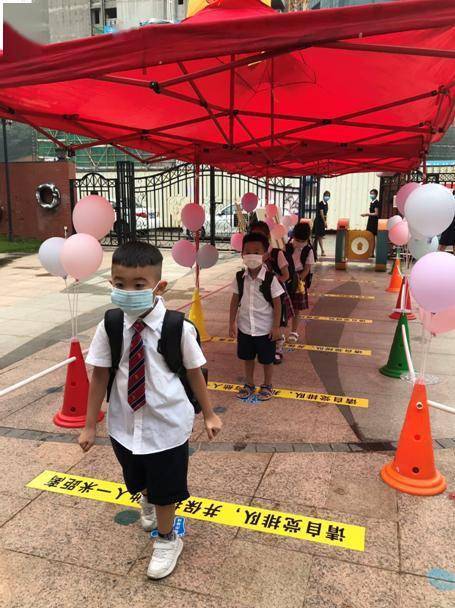 博雅幼儿园家长和小朋友在门口缓冲区间距一米排队错峰入园.