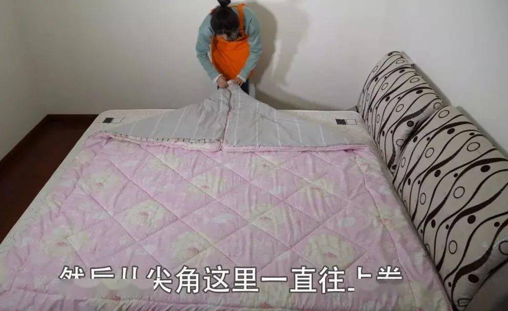被子平铺好后,我们再抓起被子的两个角将它折成三角形