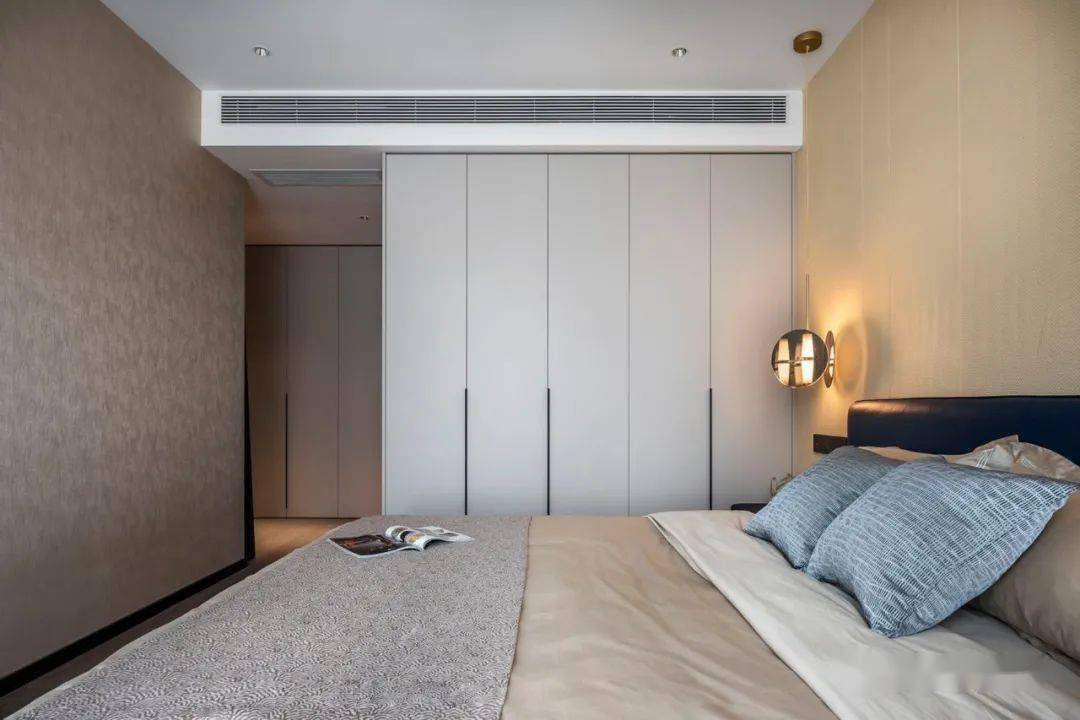 房间大面积运用温柔米色,配以百搭的白色衣柜,在床头灯的暖光笼罩中