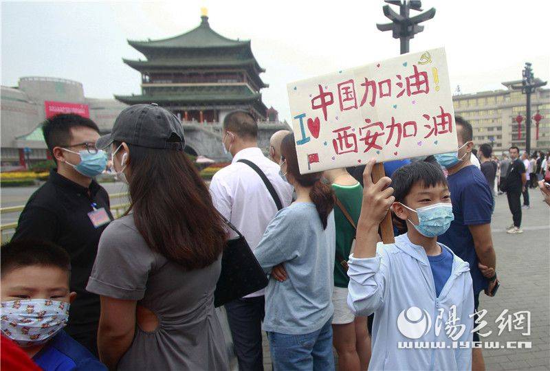 9岁的李锟从枣园西路赶到钟楼观看火炬传递,人群中他举着"中国加油!