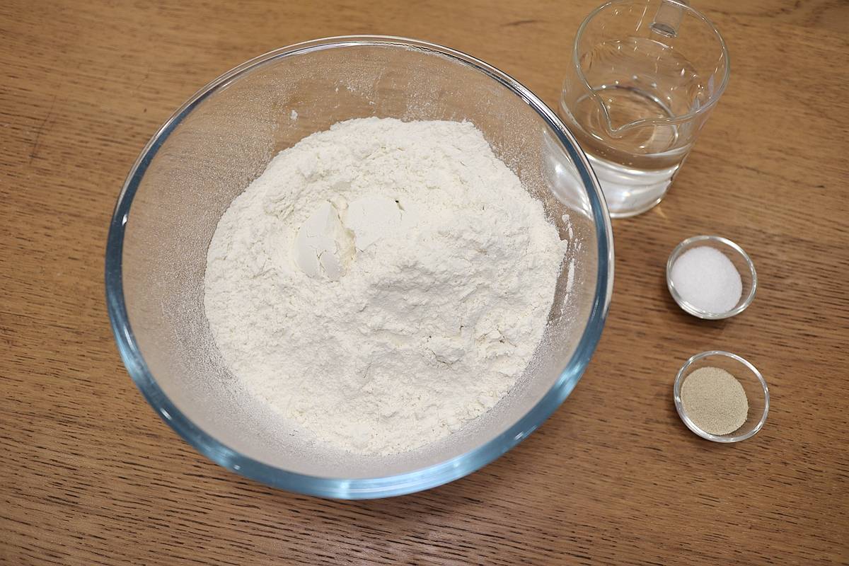 将干酵母,白糖倒入面粉中,水逐量倒入其中,先静置2分钟,让酵母融辉谮