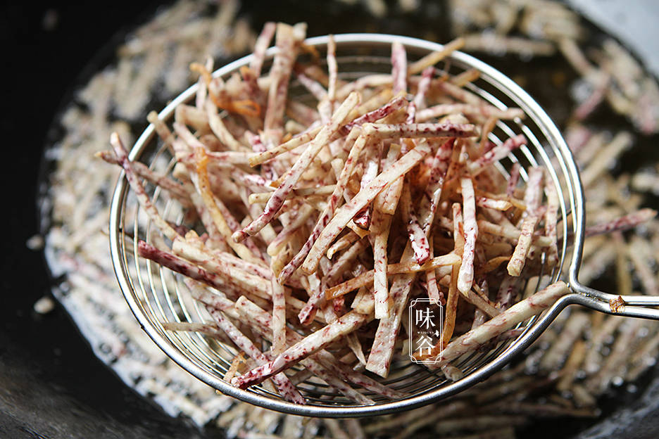 4,锅内放入少许油烧热,先下小米椒炒出辣味,再倒入炸好的芋头丝煸炒