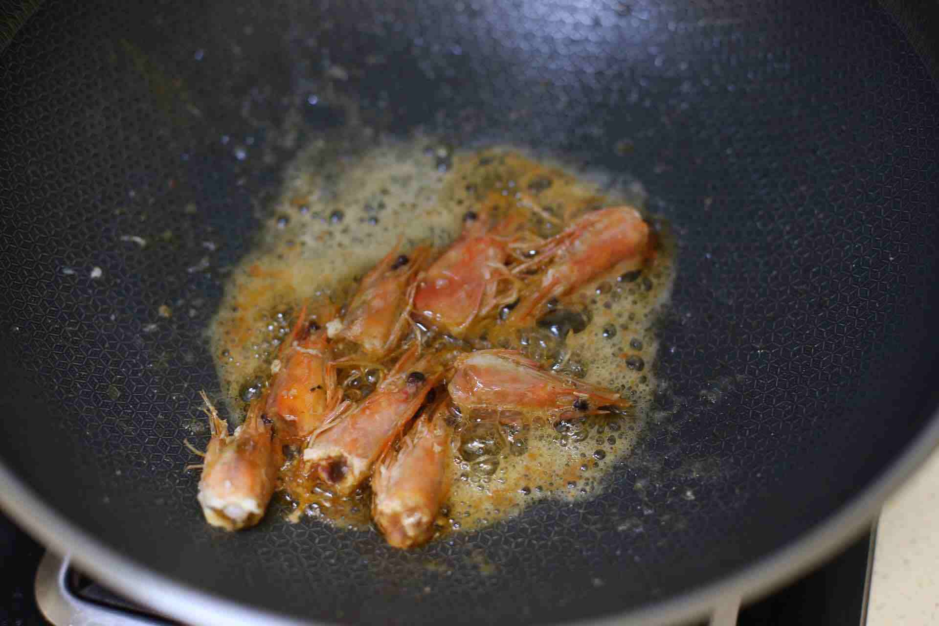 2. 起锅油热后,放入虾头煸炒出虾油.