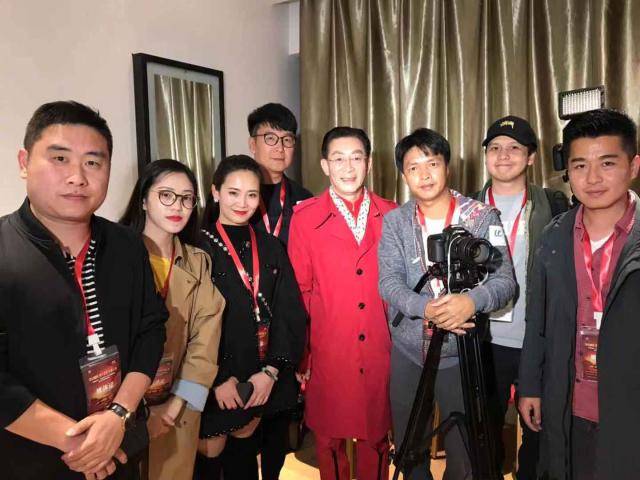 之前参加活动,六小龄童与工作人员亲切合影,身穿红色风衣妥妥成了画面