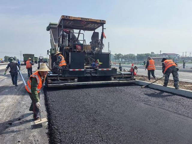 当日,项目部的建设者们,踩在155度的沥青路面,伴随着摊铺机和压路机的