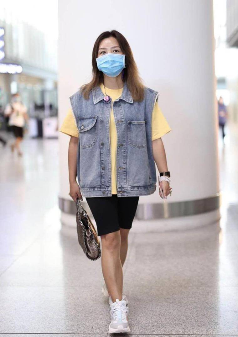 何洁身穿一件淡黄色的短袖外套,上身是一件蓝色的牛仔外套.