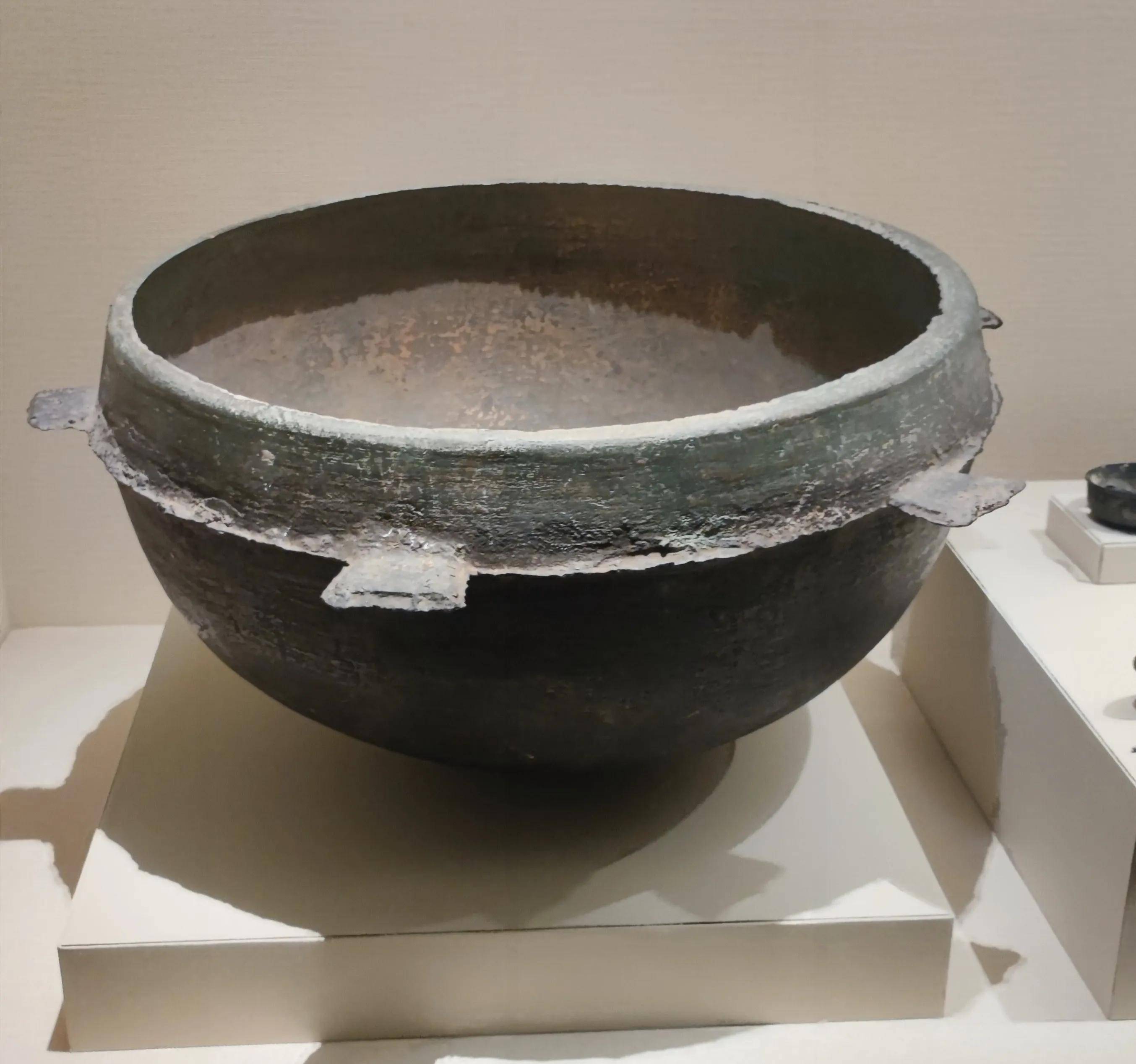 在这个展柜里,您能够看到一口大铜锅和几面大铜镜,它们呢就是金朝金属