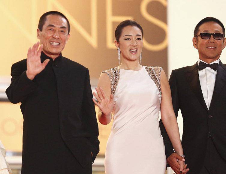 巩俐和陈道明身着优雅的白色礼服,手牵手走上红地毯,张艺谋无奈一笑
