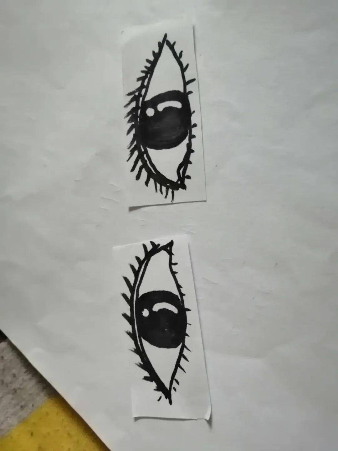 把这两个方形折出两个平行的折痕,让这两条折痕正好把你画的黑眼珠