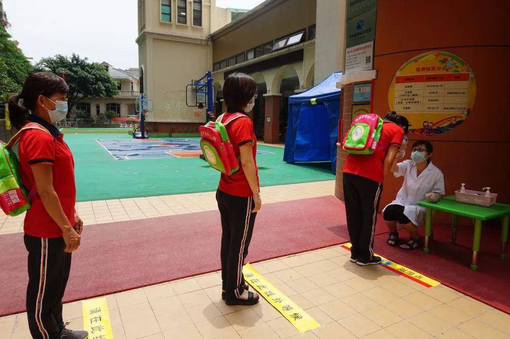 家长们有序送幼儿来园,戴口罩,保持一米距离排队,首先在大门口进行