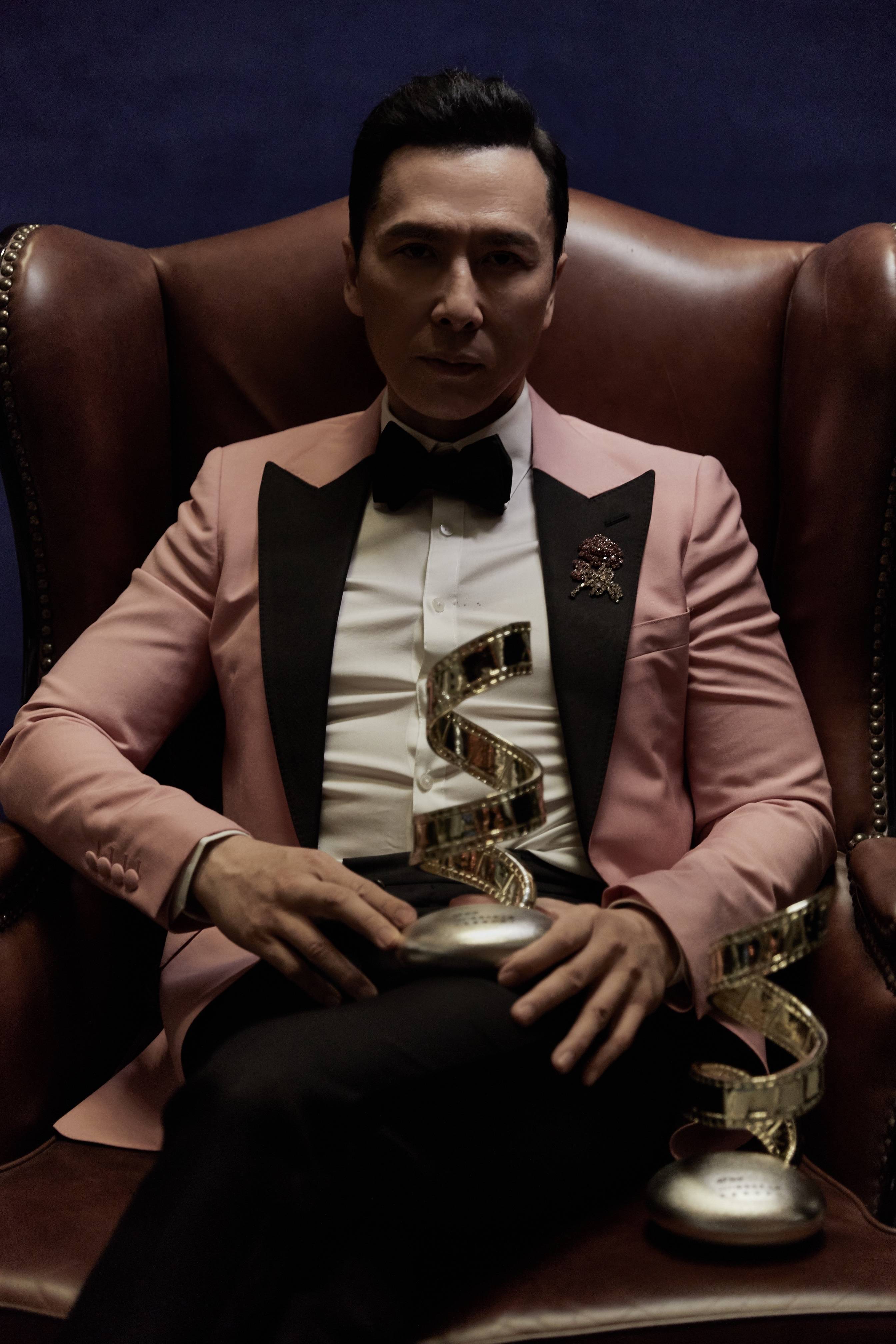 颁奖现场,甄子丹身着白底衬衫和粉色西装,搭配黑西裤与黑色小领结