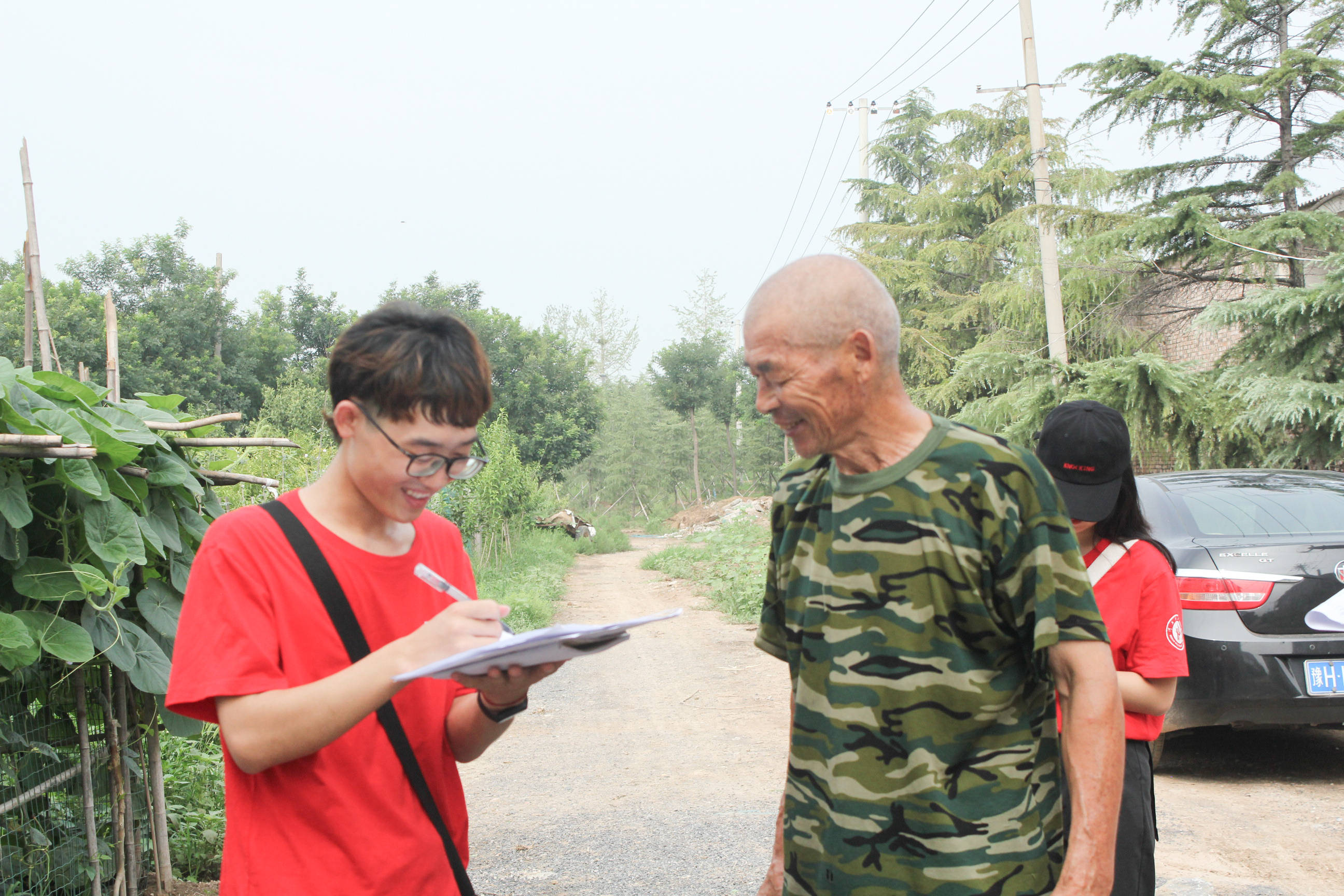 图为志愿者与正在散步的铁匠庄村村民进行问卷调查.