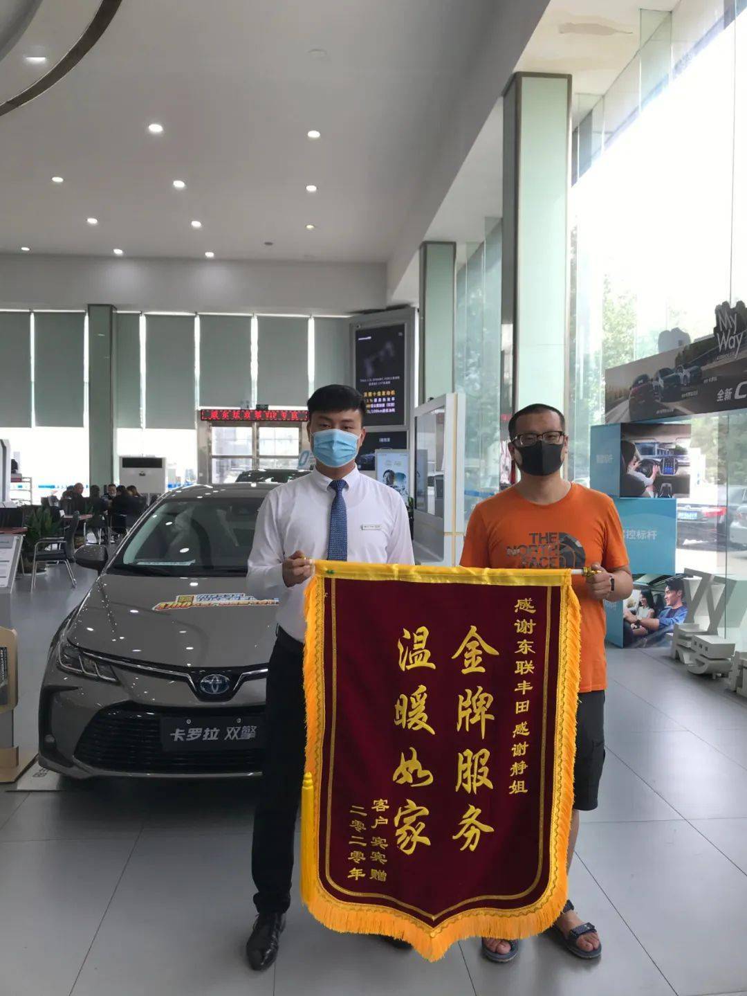 客户宾宾将一副写有"金牌服务 温暖如家"的锦旗送到东联丰田销售部