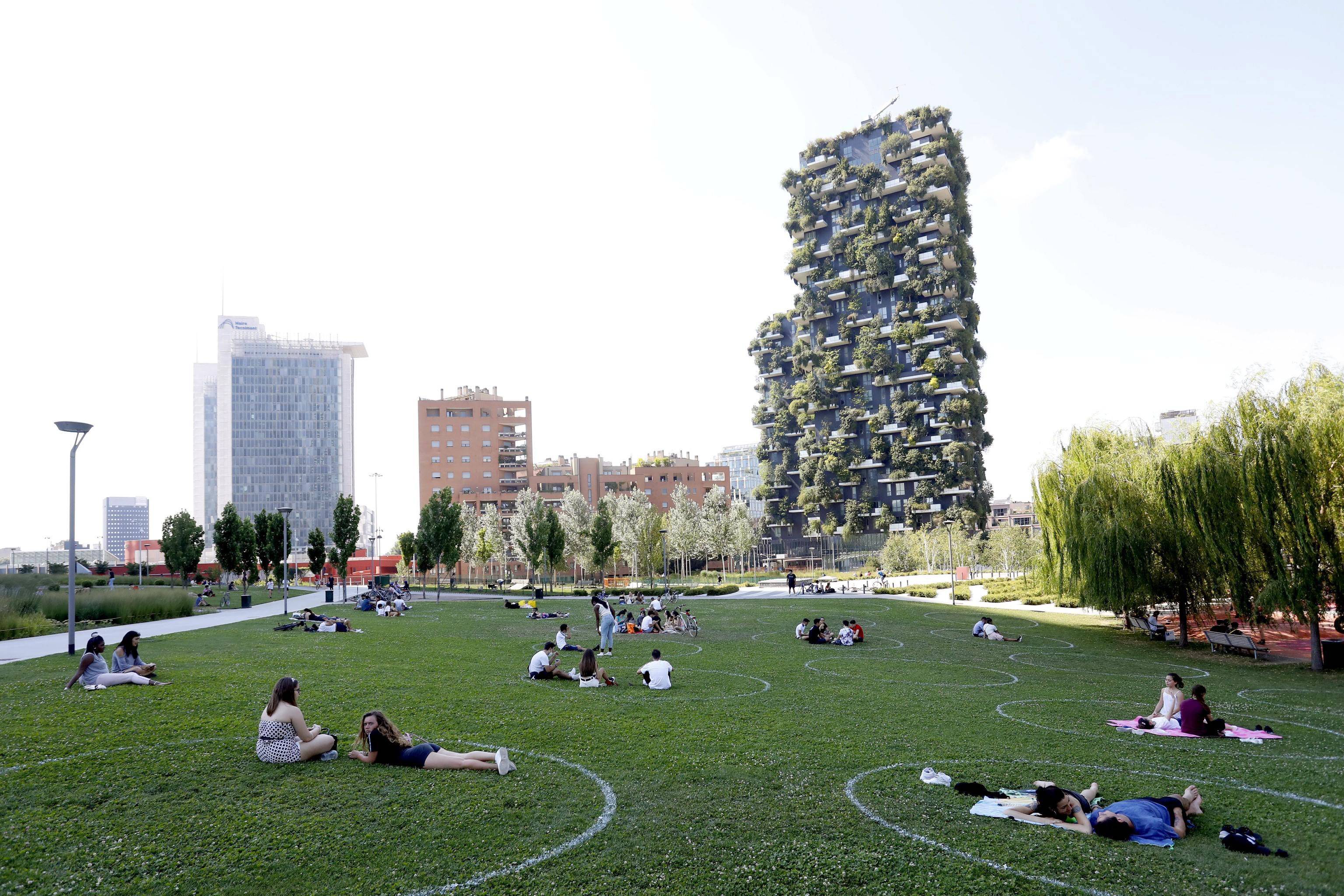 6月29日,人们在意大利米兰的一处草坪上画出的圈内休息.