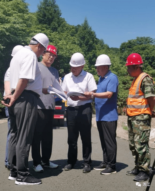 在农村道路施工现场,王代刚对区交通局负责人等随行