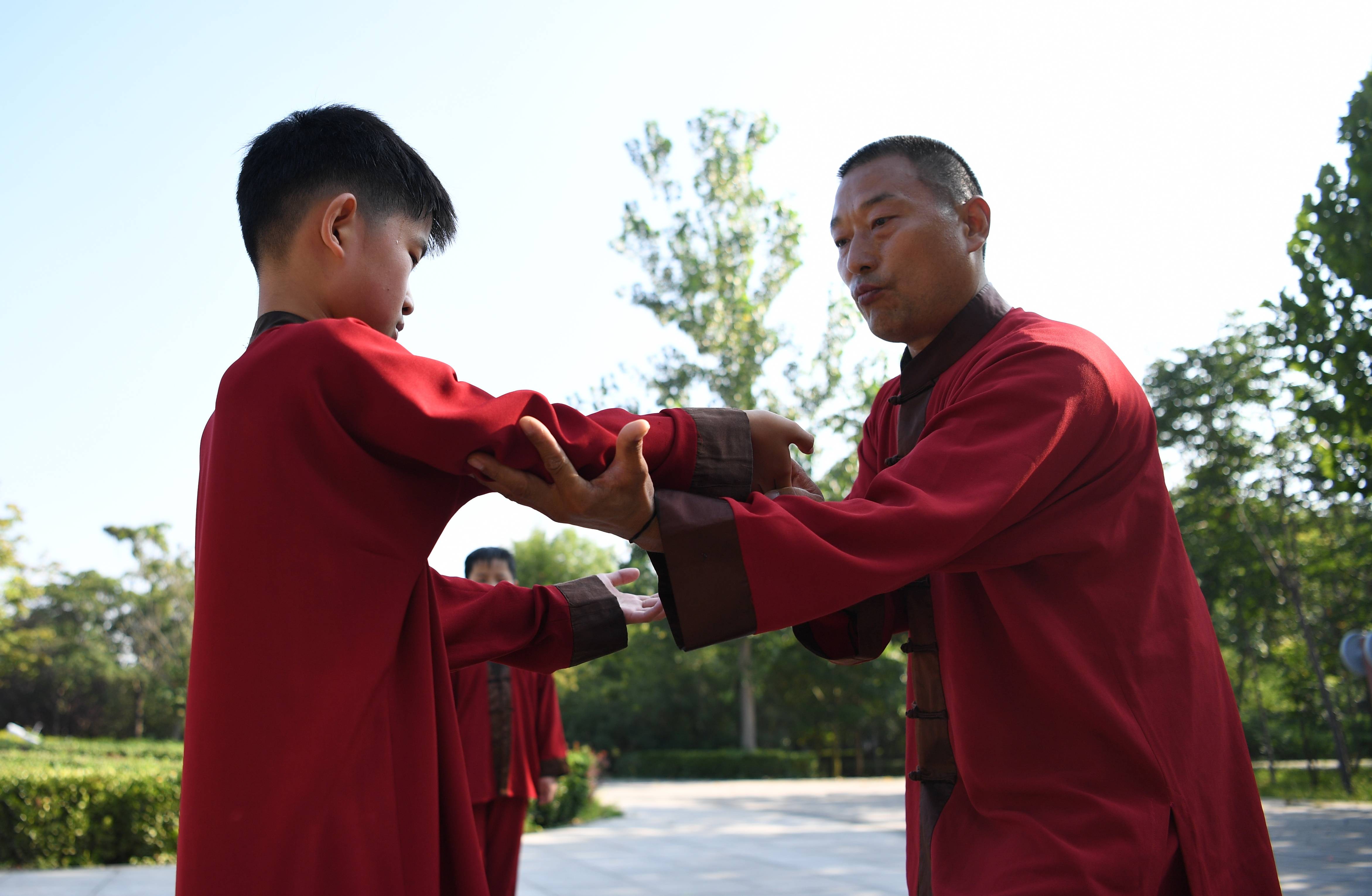 7月24日,太极拳教练檀俊强(右)在指导一名少年学员练习太极拳.