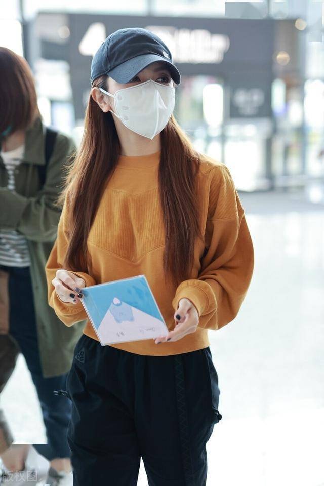 邓紫棋穿橘色卫衣现身机场,头戴棒球帽依旧挡不住她的魅力