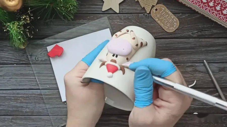 用红色软陶片塑出围巾造型,粘贴在牛的脖子上.