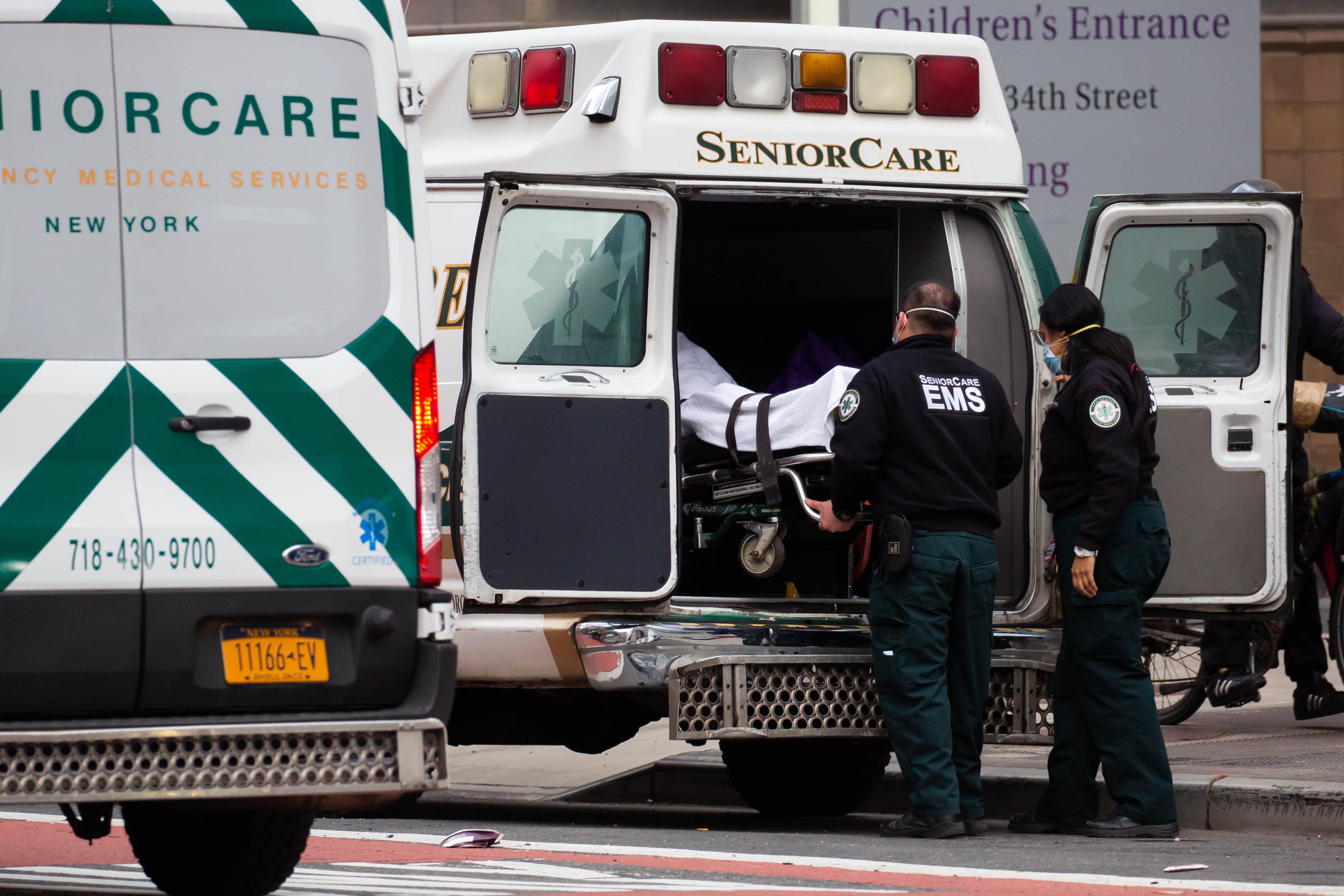 在美国纽约一家医院外,医护人员将一名患者送上救护车