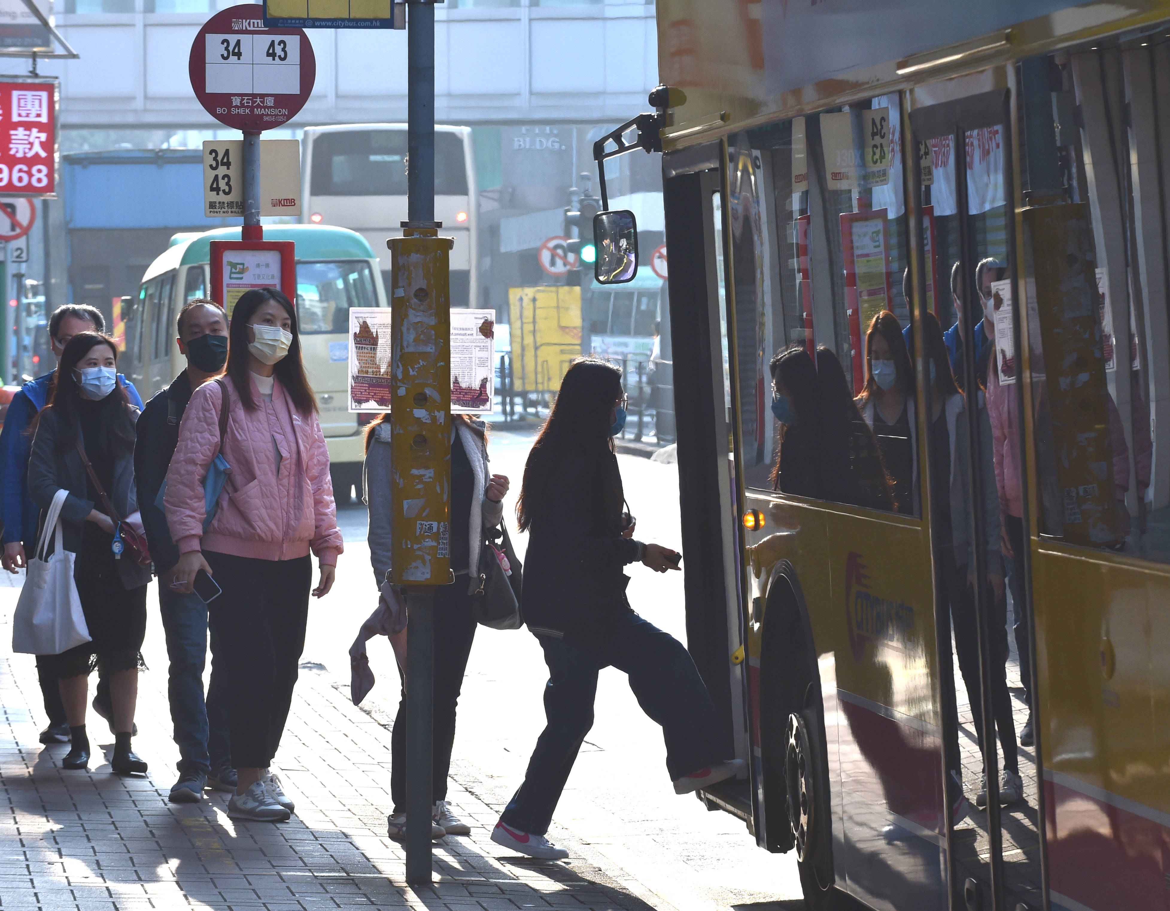 1月26日,戴口罩的香港市民排队搭乘巴士.