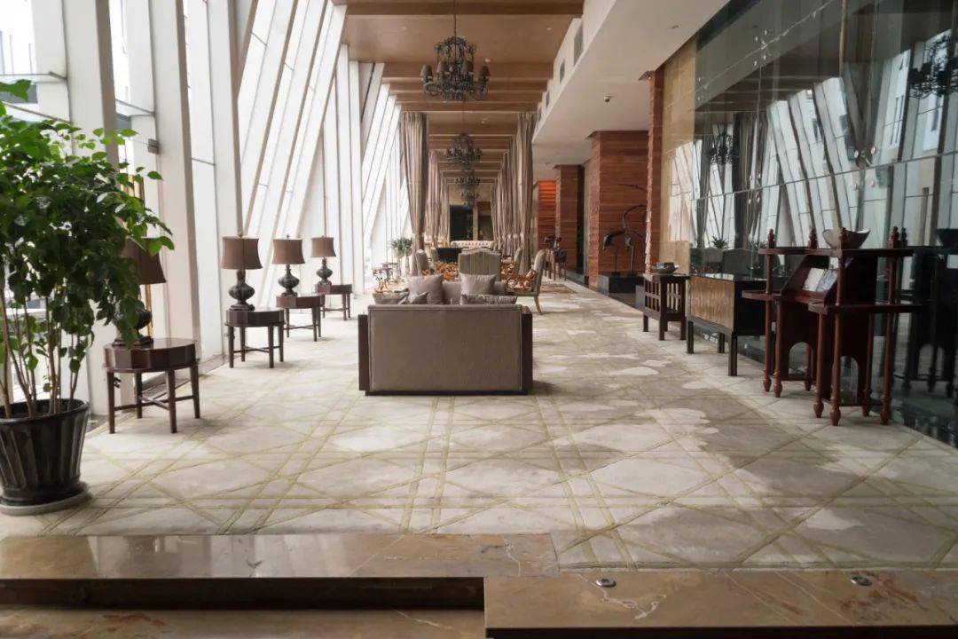 酒店大堂地面选用古木纹和国产啡网大理石拼成连续方形图案进行铺贴