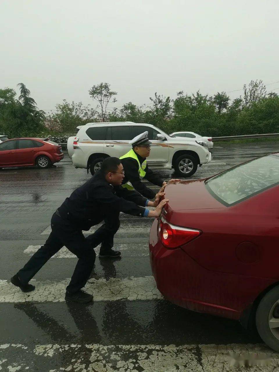 我為群眾辦實事雨天路滑車拋錨費縣交警幫忙推車除隱患