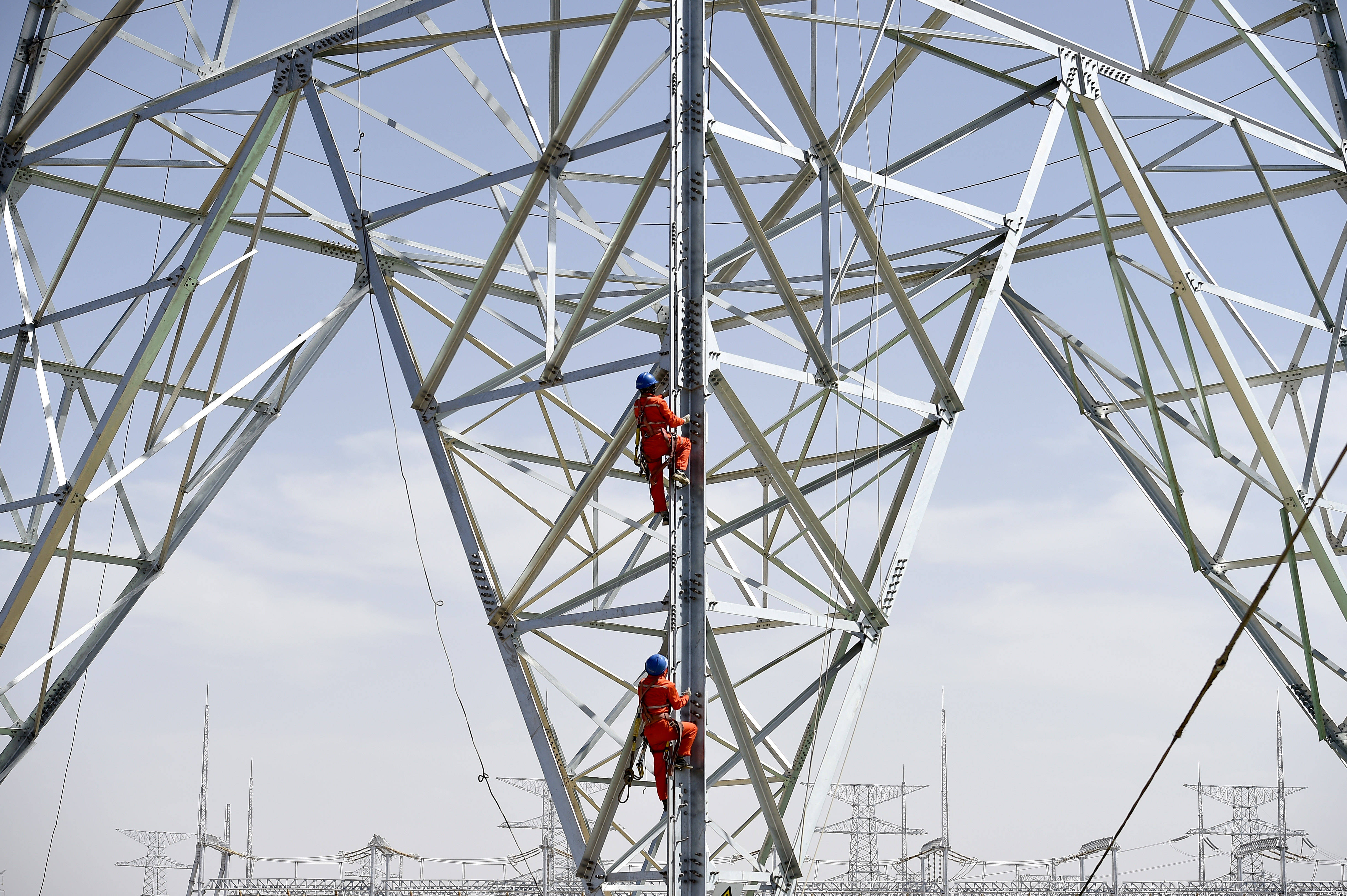 5月27日,在妙岭750千伏变电站施工现场,电力工作人员攀爬输电杆塔