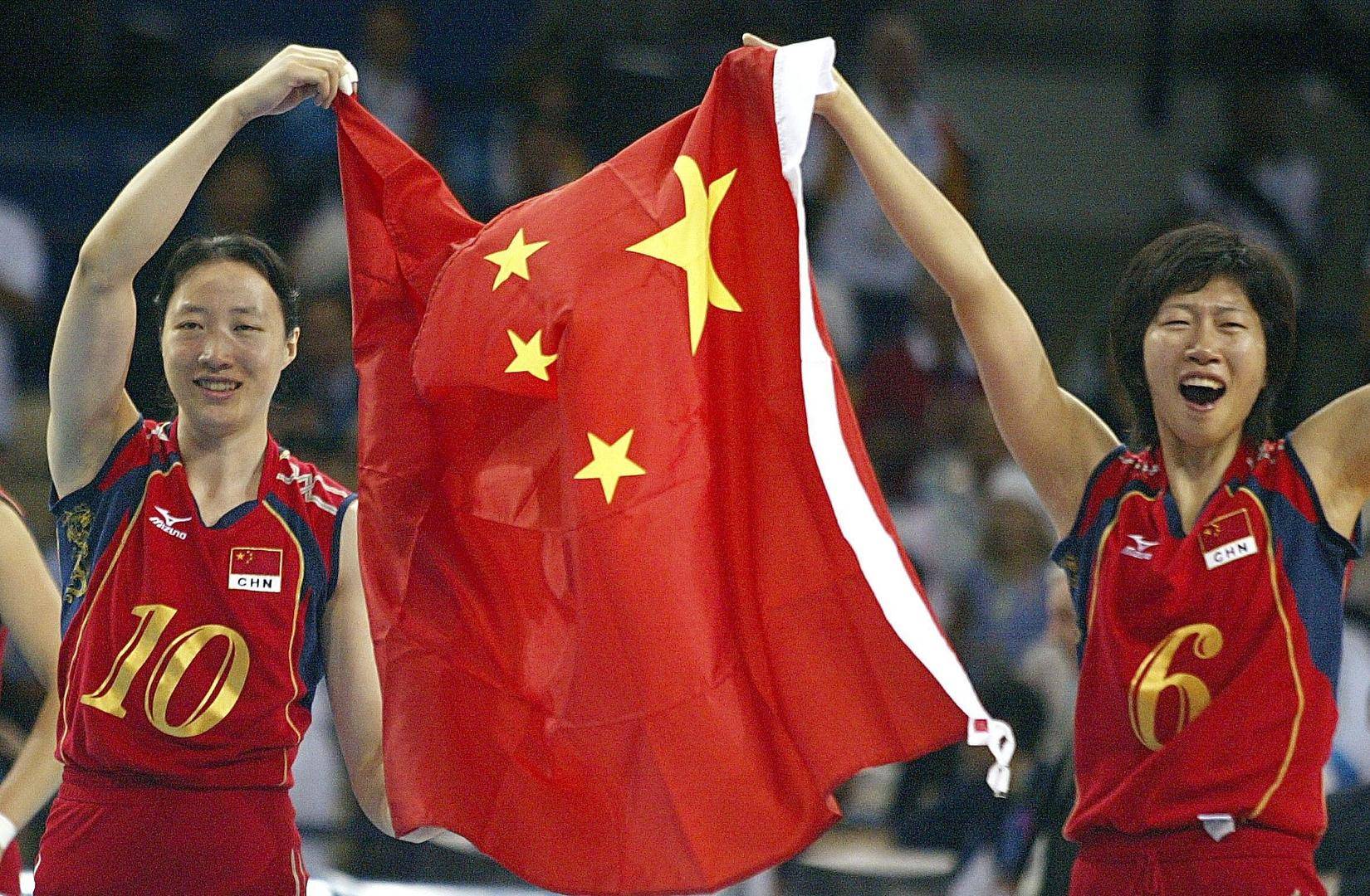 2004年雅典奥运会女排决赛后,中国女排队员陈静(左)与李珊举起国旗