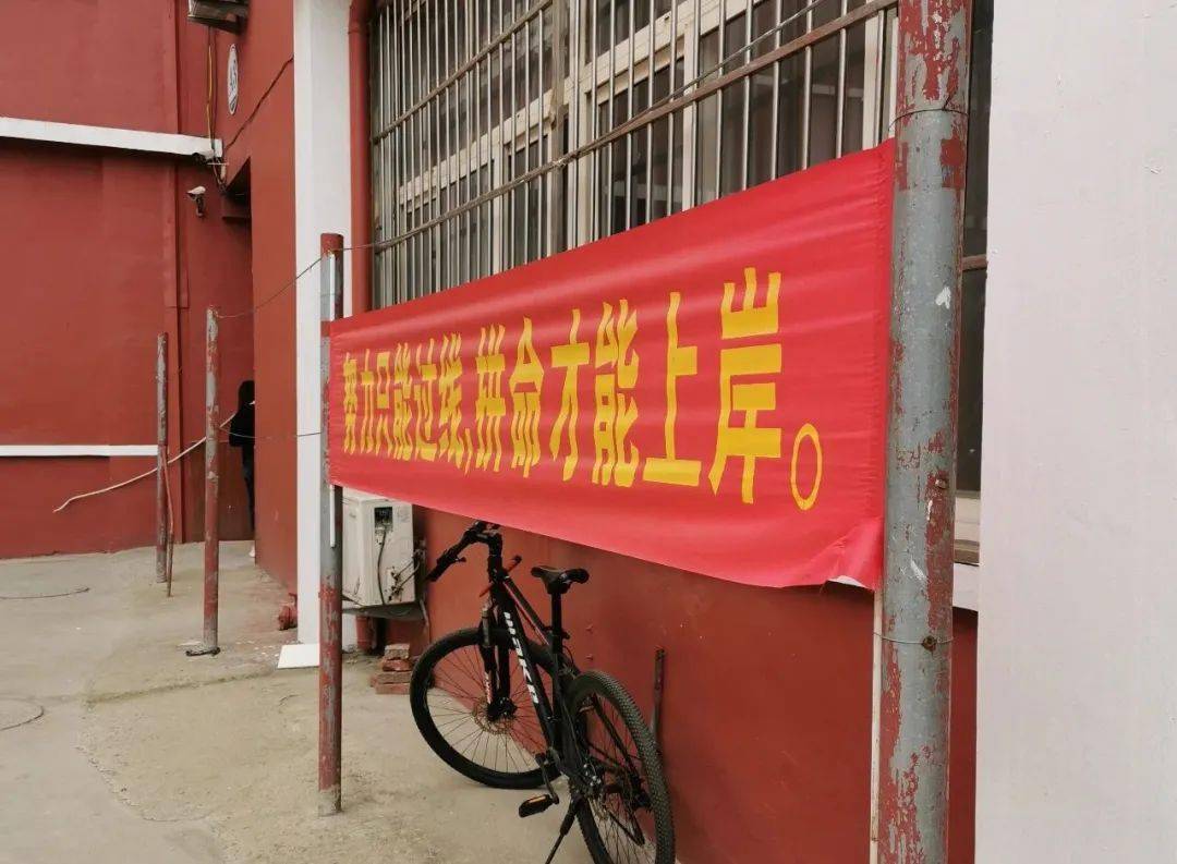 设计理论或者考研红宝书;院子里立着的铁管之间被拉起横幅,红底黄字写