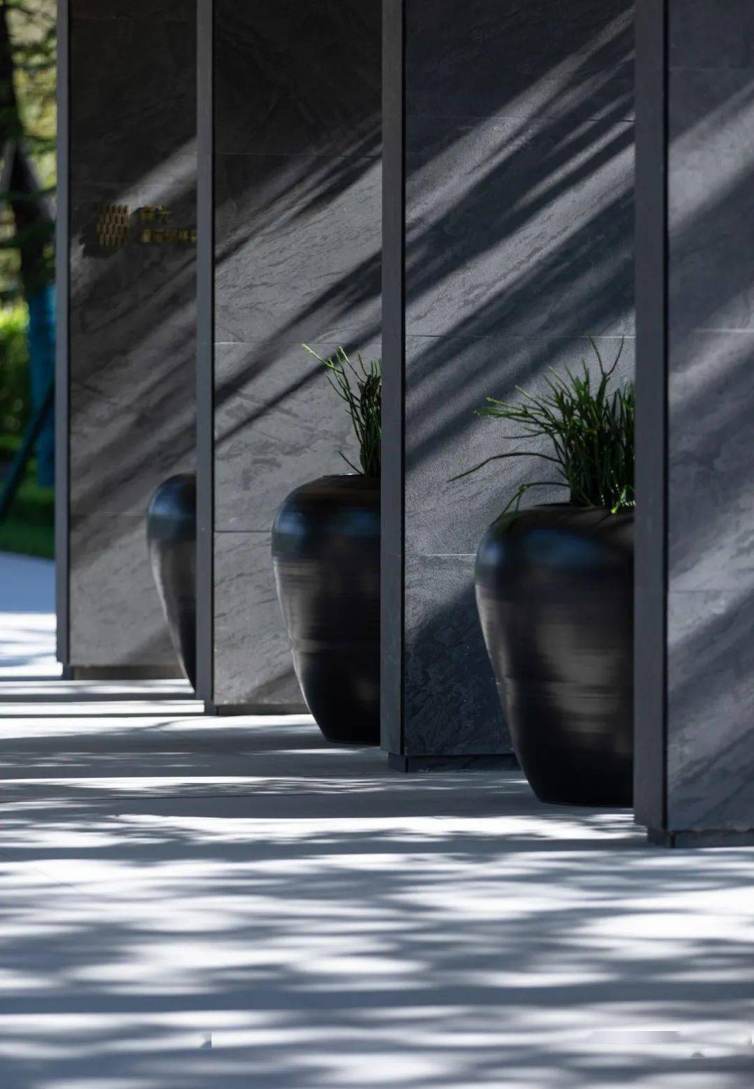 入门处的景墙与门廊,立面选用仿白木纹砖,米白色铝板,玻璃砖等材料,将