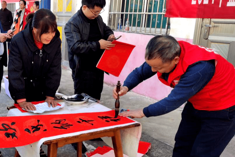 市文化馆志愿者一边书写春联,一边为热心的书法爱好者讲授书法技艺