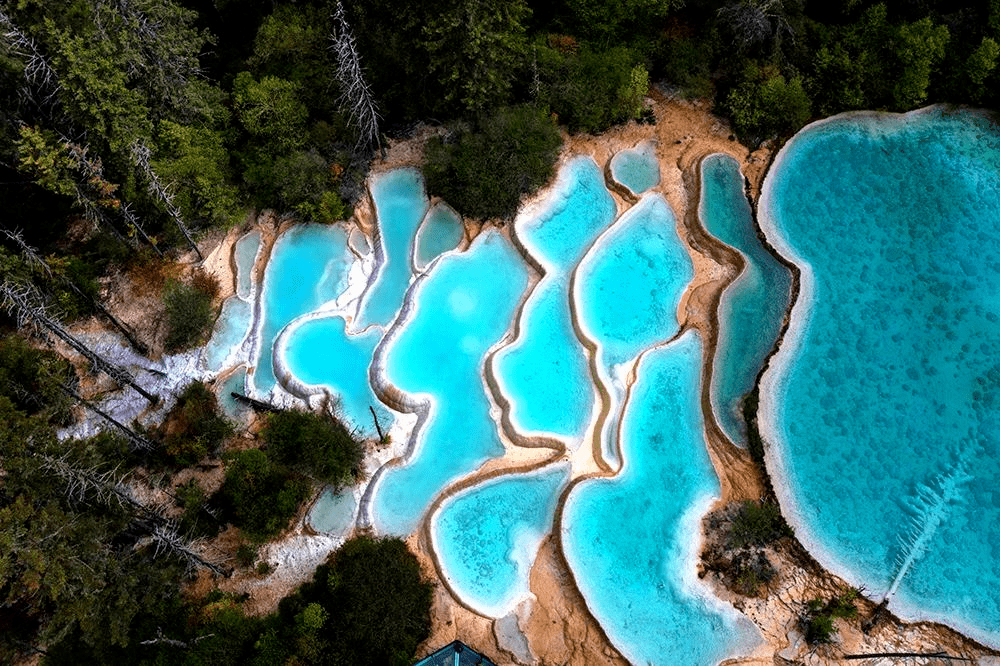 成片的山坡被黄色,乳白色钙质包裹钙化台池海子像绿色宝石,钙化池像玉