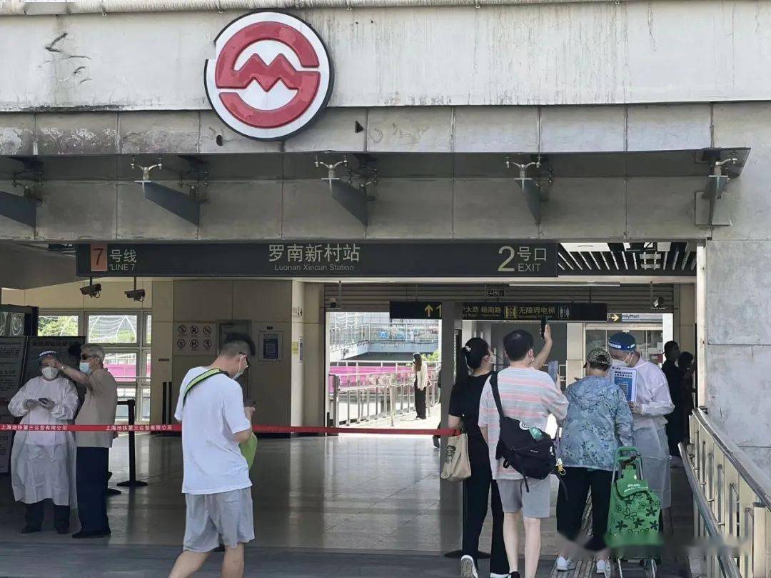 7号线罗南新村站2号口处,志愿者手持移动进站码为高峰期间进站乘客