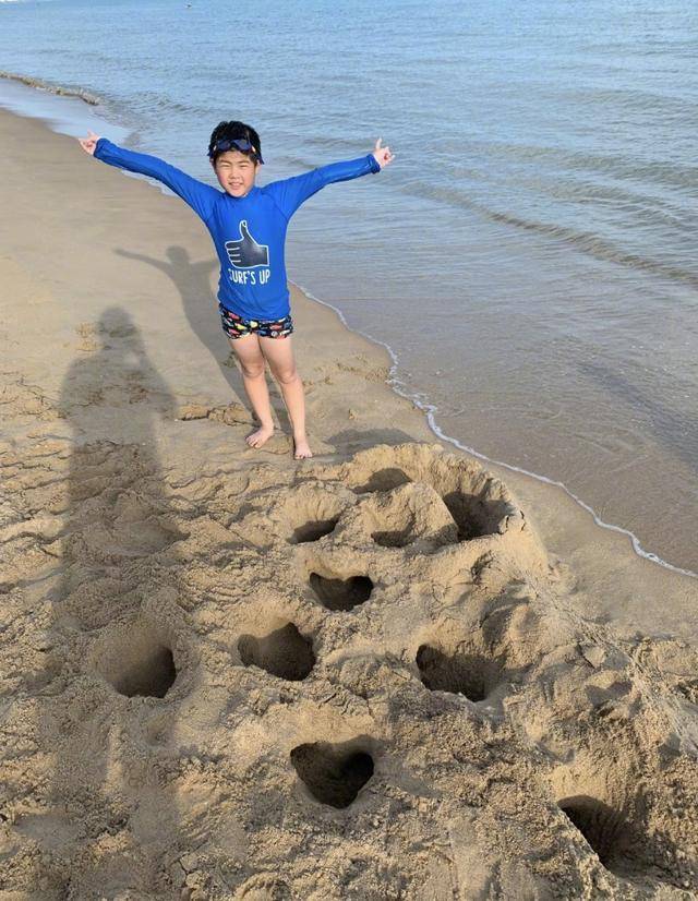 沙溢放的是旧照,安吉穿着蓝色泳衣,在沙滩上摆pose,头上还戴着游泳