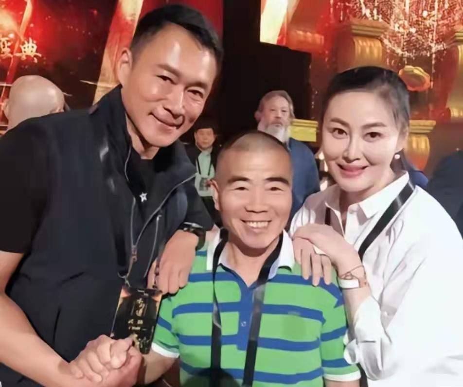 王思懿身着红色礼服裙外面套着一件卡其色风衣,笑魇如花地站在丁海峰