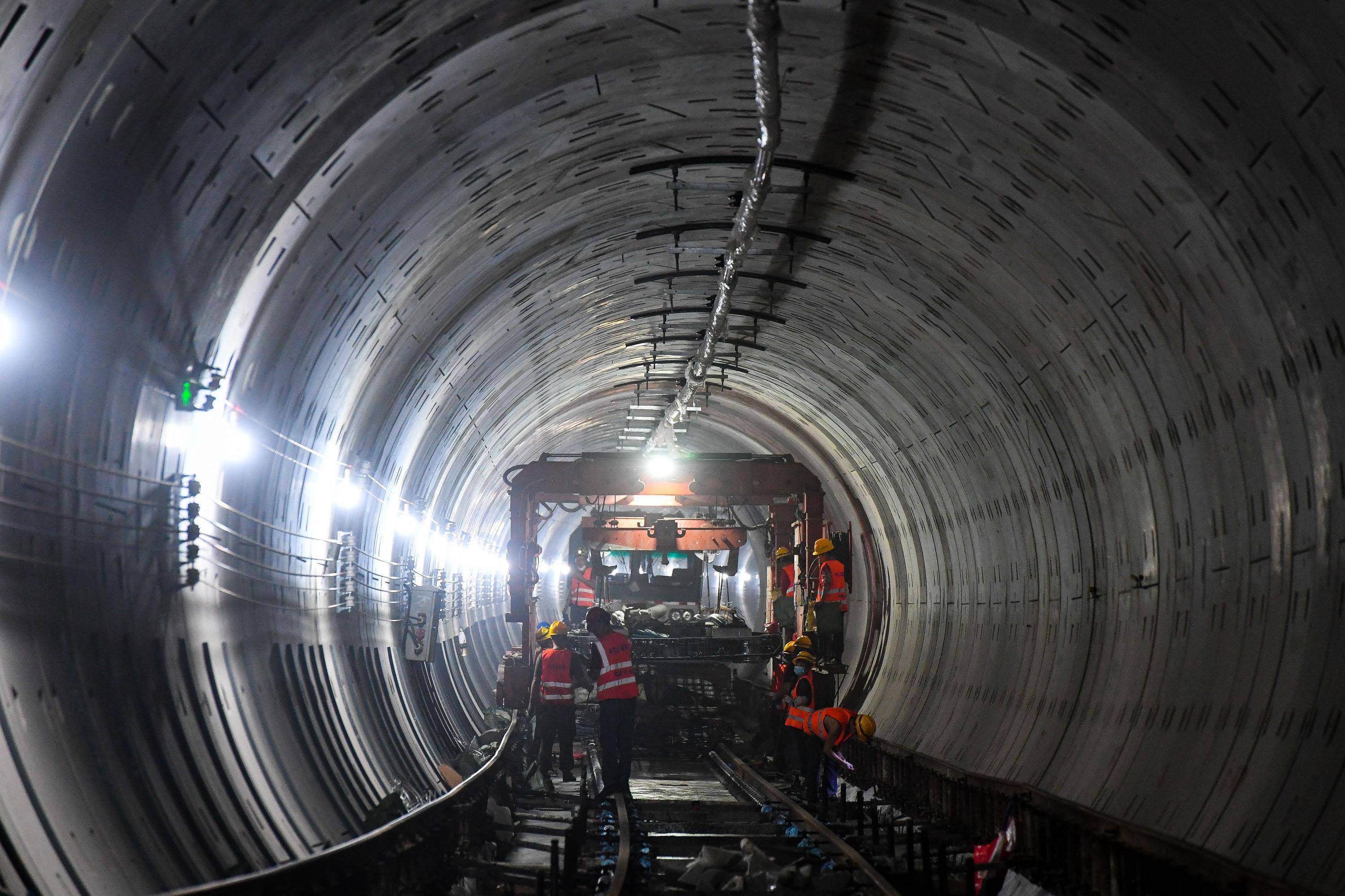 10月26日,施工人员在广州地铁11号线隧道内吊装轨排.