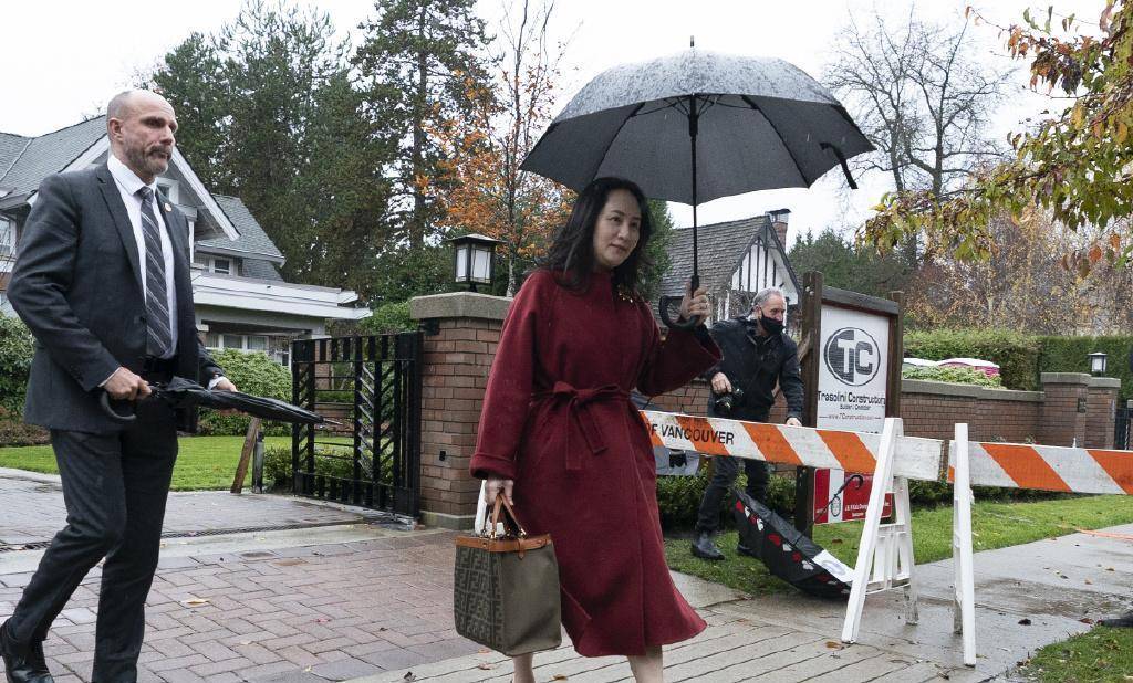 孟晚舟一袭红大衣再次现身,雨中撑伞从容大气,脸上依然满脸笑容_气质