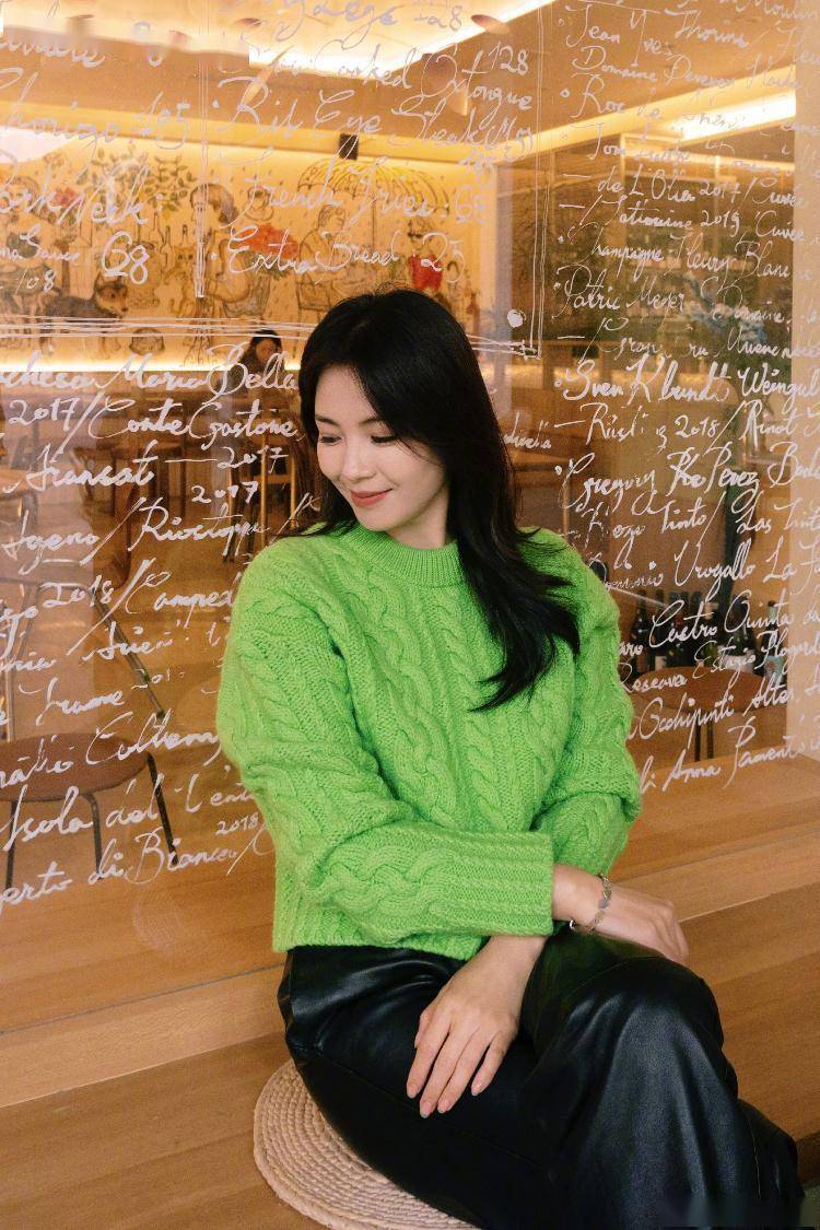 她披散长卷发,身穿绿色毛衣搭配黑色皮裤,双手比耶灿笑可爱满分