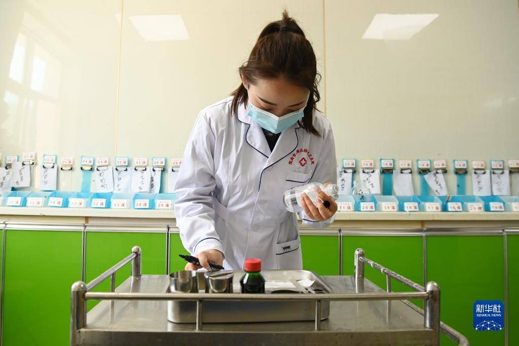 在武都区桔柑镇卫生院住院部护士站，李瑞给患者配药（5月11日摄）。新