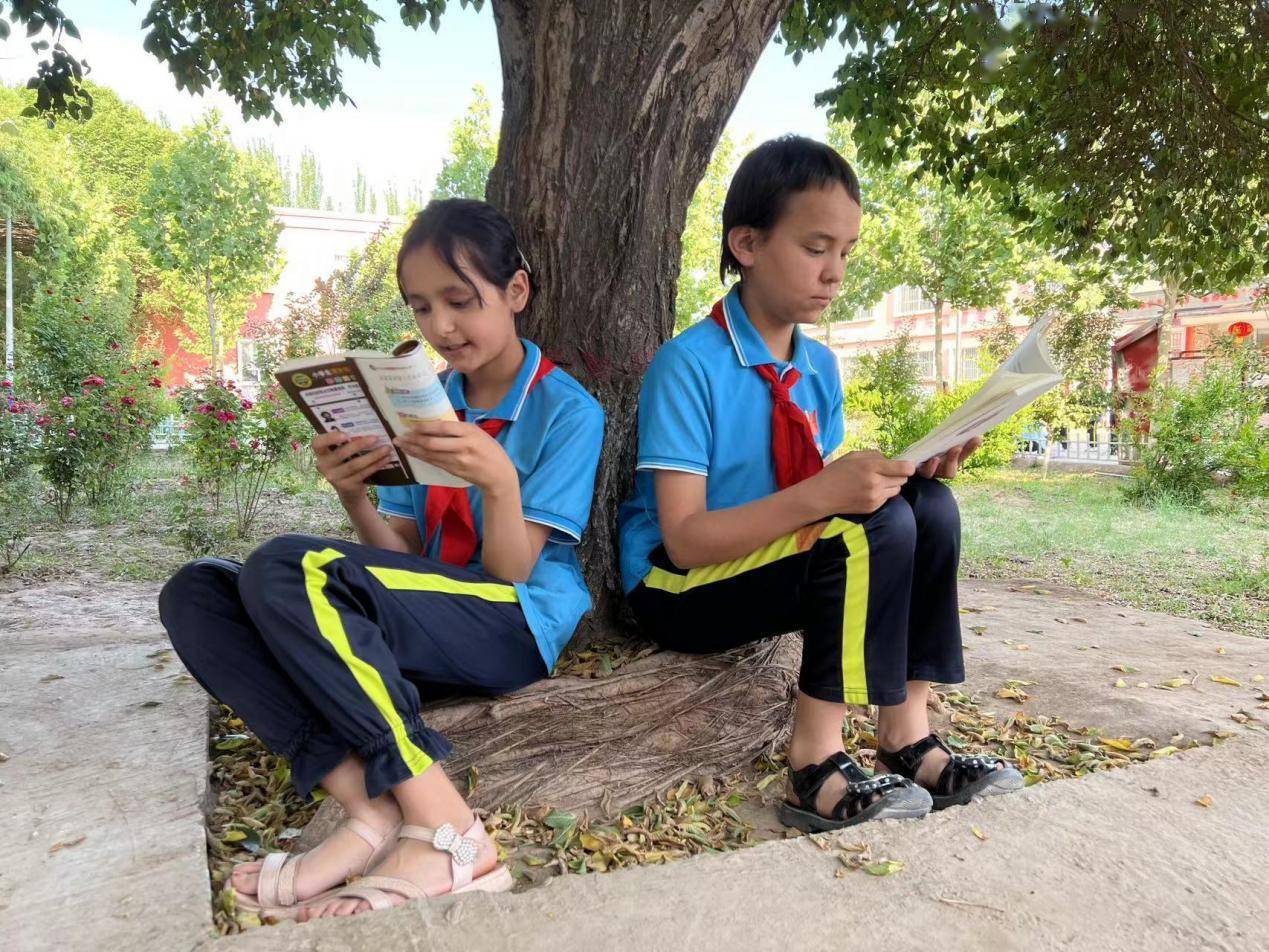 伽师县江巴孜乡第一小学的学生们在室外阅读.