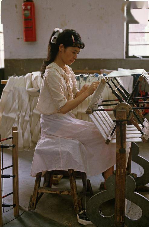 6,一位打扮时髦的女工,她坐在椅子上,用脚踩着踏轮,带动了上方的卷轮