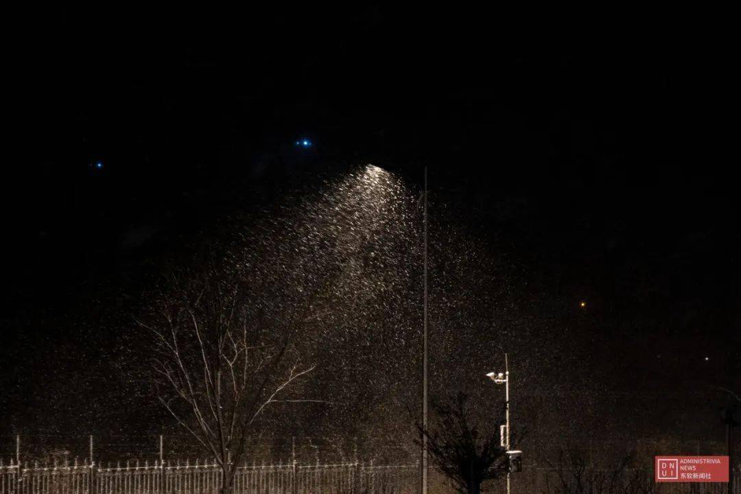 若隐若现朦胧在暖光里划过橘色的路灯纷飞的雪花夜色为雪景施了魔法